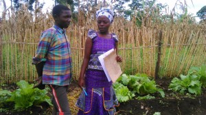 Garden shop employee Teopista (right) performing a garden mentor visit with Lydia's son.